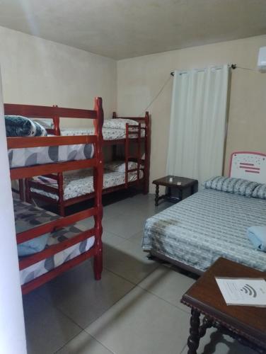 a room with three bunk beds and a table at Casa do Vans in São Gabriel