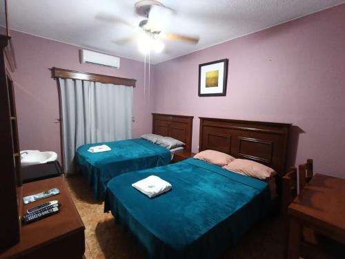 two beds in a room with purple walls at Garcia's Suites y Hotel Villegas in Linares