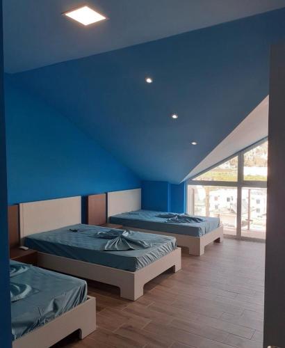 two beds in a room with a blue wall at Shengjin apartaments kozmai in Shëngjin