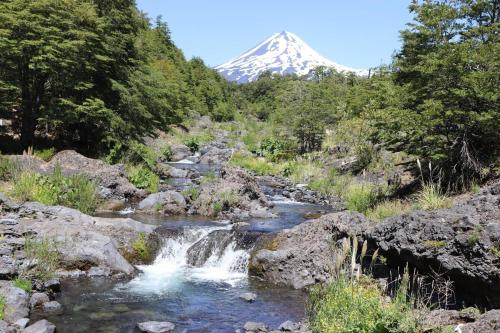 una montagna in lontananza con un fiume e una montagna di Vista al volcán con tinaja y río en Conguillío a Curacautín