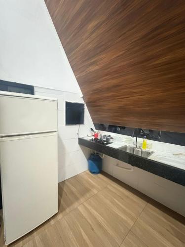 a kitchen with a white refrigerator and a wooden ceiling at In concept chalé completo in Duque de Caxias