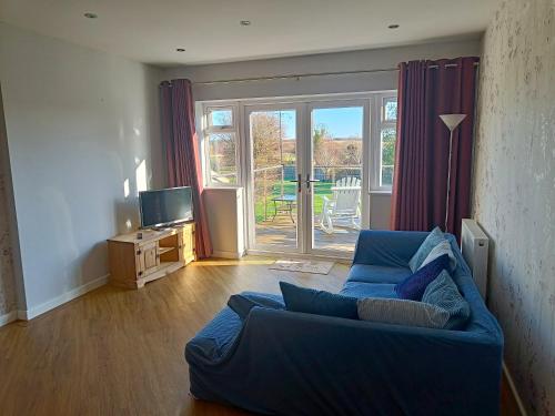 a living room with a blue couch and a sliding glass door at Countryside 2 Bed Bungalow with Stunning Views Free WiFi and Parking Ideal for Business and Leisure in Great Addington