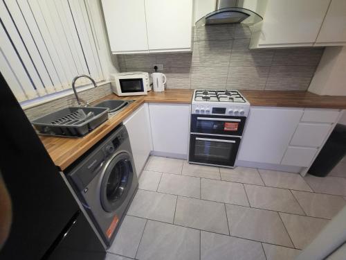 a kitchen with a stove and a washing machine at Modern North Shields Home - Perfect for Short or Long Stays in Newcastle upon Tyne