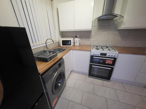 a kitchen with a stove and a washing machine at Modern North Shields Home - Perfect for Short or Long Stays in Newcastle upon Tyne