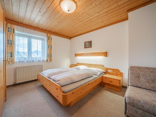 een slaapkamer met een houten bed en een stoel bij Kitzsteinhorn in Kaprun