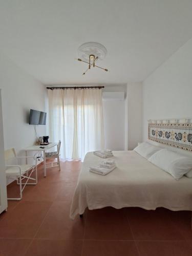 een witte slaapkamer met een bed en een bureau bij Casa del Sole Guest House in Alghero