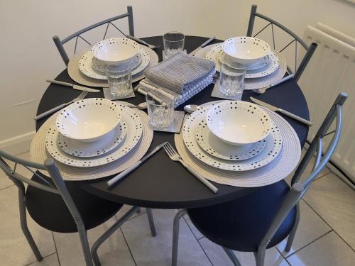 a black table with plates and bowls and glasses at Modern North Shields Home - Perfect for Short or Long Stays in Newcastle upon Tyne