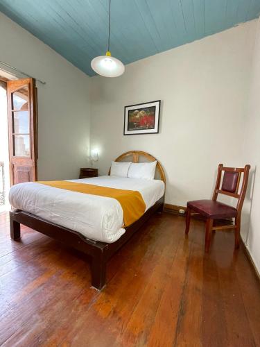a bedroom with a large bed and a chair at Hostal Lluvia de Oro in Arequipa