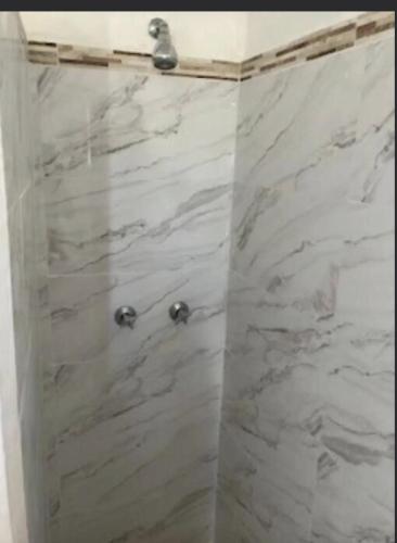a shower with white marble walls and chrome fixtures at Uniek Villa in Gros Islet