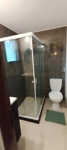 a bathroom with a glass shower and a toilet at Doce lar in Búzios