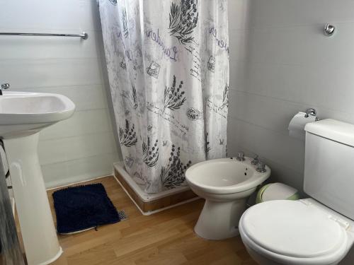 a white bathroom with a toilet and a sink at Cabaña, Sol y Paz in Lima