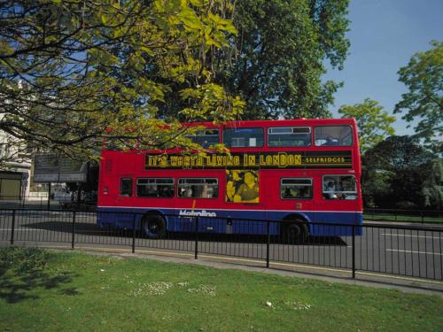a red double decker bus driving down a street at ibis London Sutton Point in Sutton
