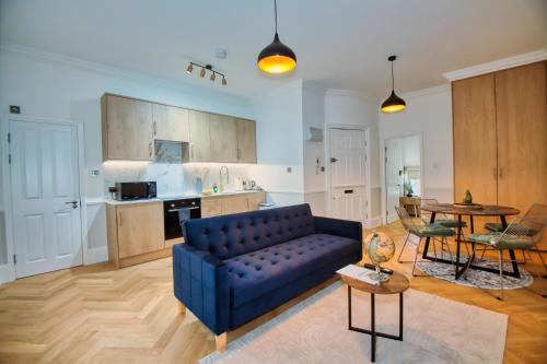 a living room with a blue couch and a kitchen at RoyalPark Apartments in London