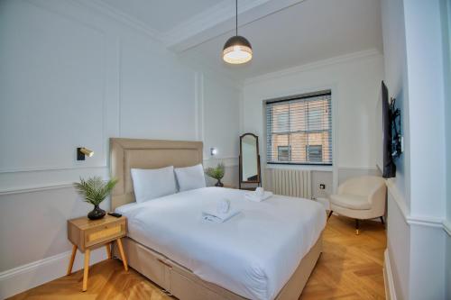 a bedroom with a large white bed and a chair at RoyalPark Apartments in London