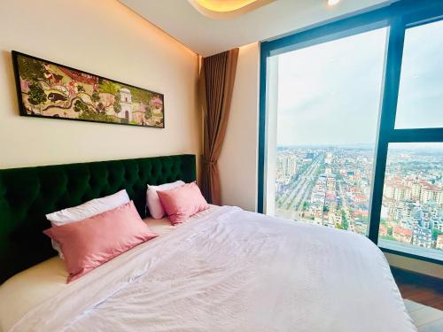 een slaapkamer met een bed met roze kussens en een raam bij 2-bedroom Doji apartment in hai phong in Hai Phong