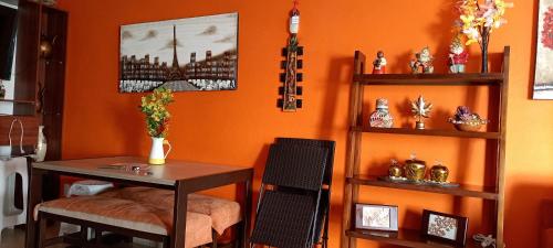a room with an orange wall with a table and a shelf at Casa Adhita, tú confort es nuestra prioridad. in Yautepec de Zaragoza