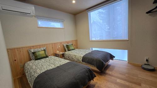 a bedroom with two beds and a large window at Hakuba Powder Cottage Eden in Hakuba