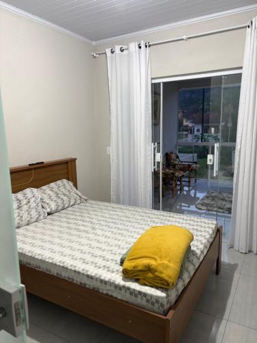 a bedroom with a bed with a yellow pillow on it at Casa aconchegante à 2 minutos da praia em Prainha de Mambucaba Paraty in Paraty