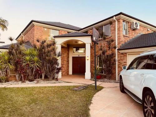 a white car parked in front of a brick house at Carindale family home, private pool, leisure accommodation in Brisbane