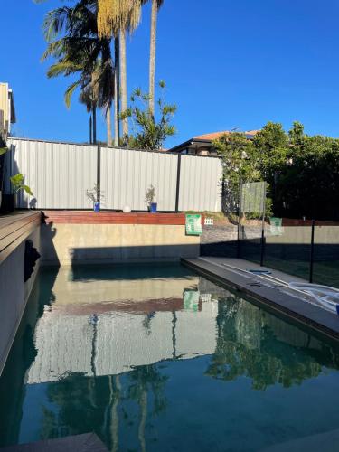 a pool of water with palm trees and a fence at Carindale family home, private pool, leisure accommodation in Brisbane