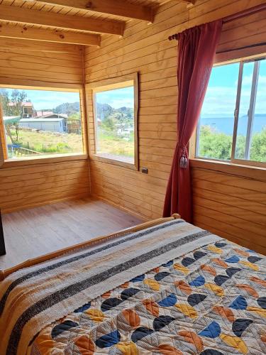 a bedroom with a bed in a room with windows at Cabañas Donde Gaspar in Dalcahue