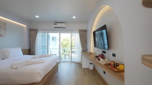 a bedroom with a bed and a television and a balcony at บ้านระเบียงทะเล หัวหิน in Hua Hin