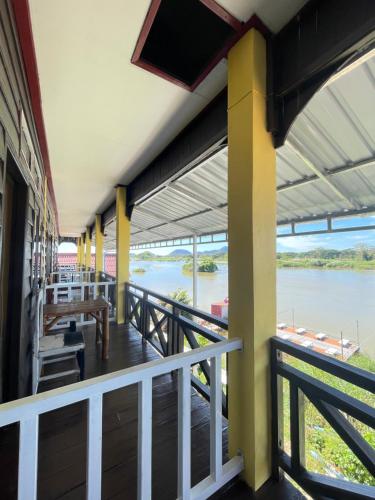 een balkon van een huis met uitzicht op een rivier bij Tena Guest House in Don Det