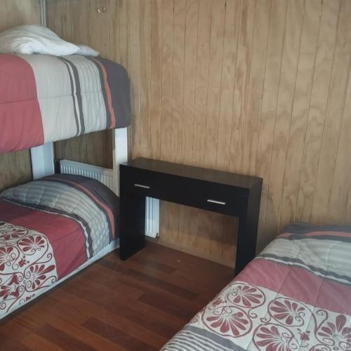 a room with two beds and a nightstand between two beds at HOSTAL CARHUELLO in Pucón