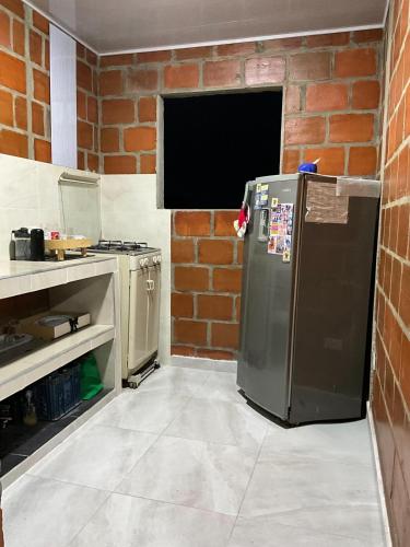 a kitchen with a refrigerator and a brick wall at The Magical Garden in Cali