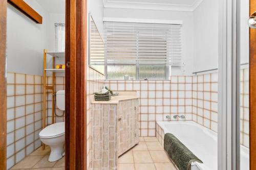 a bathroom with a tub and a toilet at Holiday house in Roleystone