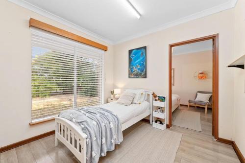 a bedroom with a bed and a large window at Holiday house in Roleystone