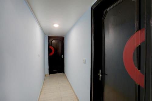 a hallway with a black door and a white wall at Hotel O Metro Residency in New Delhi