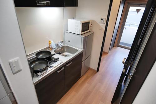 a small kitchen with a sink and a microwave at Petit Grande Nuage in Tokyo