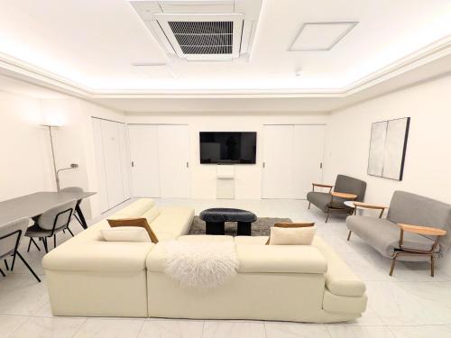 a living room with white furniture and a flat screen tv at City Hotel Namba Prime in Osaka