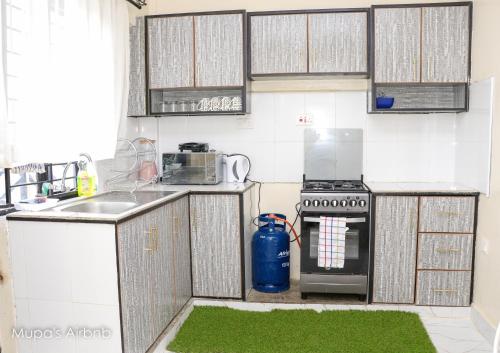 a kitchen with white cabinets and a green rug at Mupa Luxury Condo IV BnB in Nyahururu