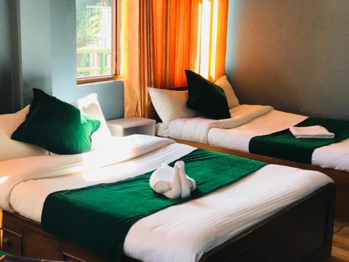 2 letti in una camera con verde e bianco di Mita Hotel a Dhulikhel