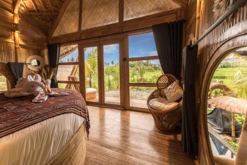 a bedroom with a bed and a large window at Lazy Coconut Bali in Gianyar