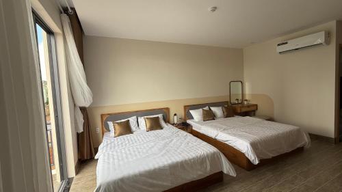 a bedroom with two beds with white sheets at Moon Hotel Buôn Hồ in Buôn Tring
