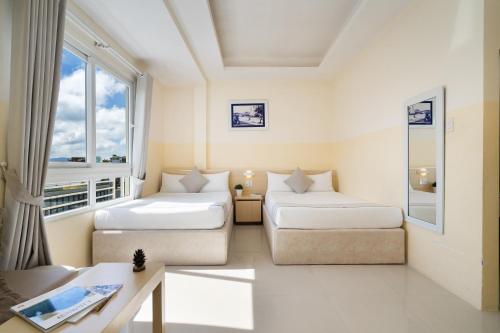 a hotel room with two beds and a couch at Ngoc Nguyen Anh Hotel Da Lat in Da Lat