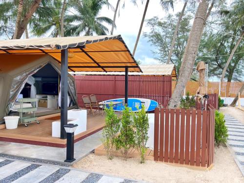 an orange umbrella on a deck with a swimming pool at Sichon Glamping Resort, Beachfront in Ban Plai Thon