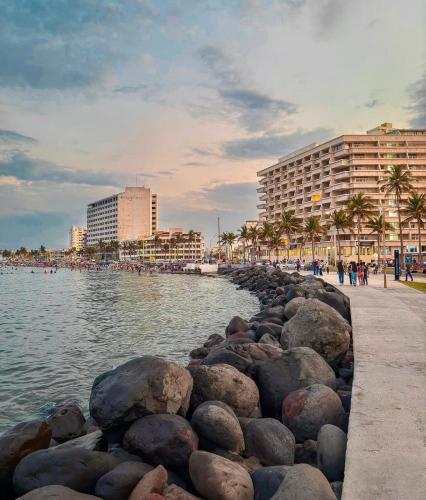 a group of people walking along a beach near the water at Puerto 201 ROOMS in Veracruz