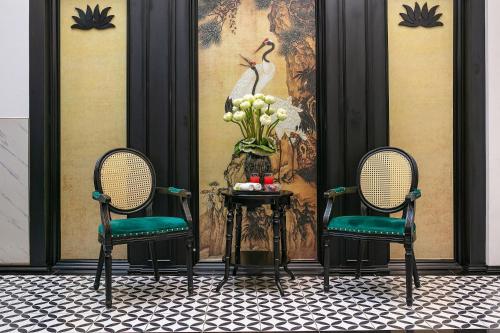 河内Ja Cosmo Hotel and Spa的两把椅子和一张带花瓶的桌子