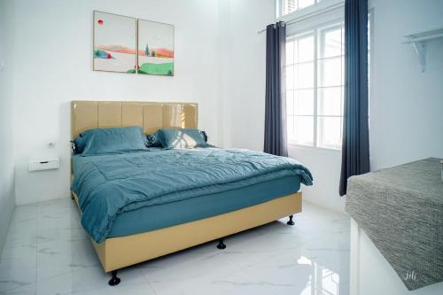 een slaapkamer met een bed met een blauw dekbed bij Pilla Villa Purwokerto in Purwokerto