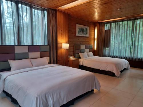 a bedroom with two beds and windows in it at Pei Kong Creek Resort in Guoxing