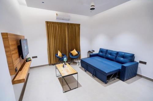 a living room with a blue couch and a tv at Nes-Terns in Coimbatore