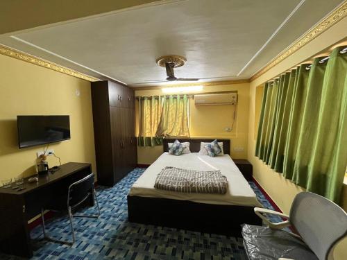 a bedroom with a bed and a desk and a television at PlatinumIN Guesthouse in kolkata