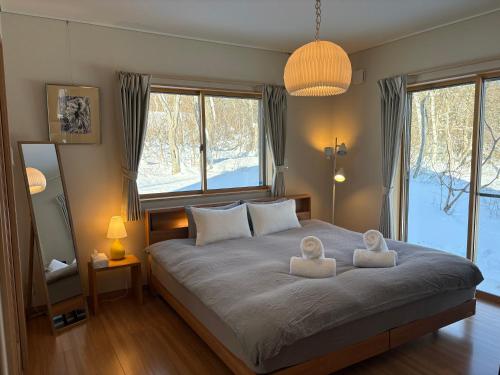 a bedroom with a large bed with two white chairs on it at Meanwhile Woods in Myoko