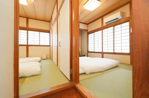 a mirror in a room with a bed and two windows at Private Tatami House 4min from Teradacho Sta in Osaka