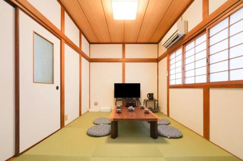 a room with a table and a tv in it at Private Tatami House 4min from Teradacho Sta in Osaka
