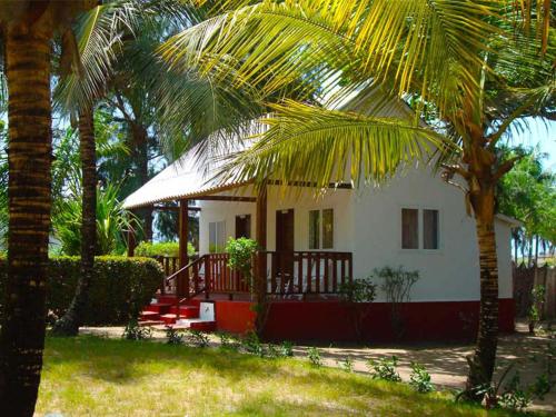 a white house with palm trees in front of it at Hotel Village Vacances Awale Plage in Grand-Popo